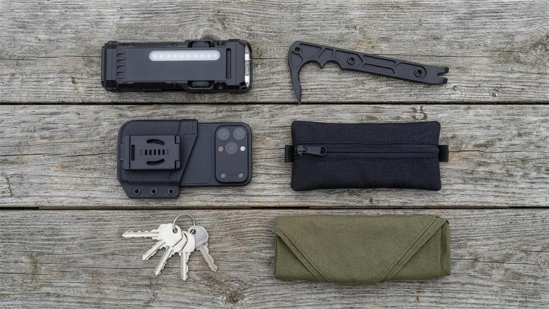 Everyday carry flat lay on wood planks: flat flashlight, rescue pry bar, belt-clip phone sheath, zip organizer, keys and a bandana (concept render)