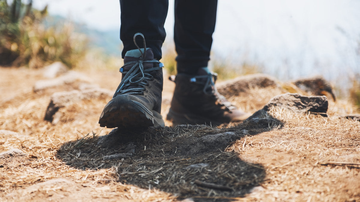 Hiking boots and trouser cuffs on a rocky rural path
