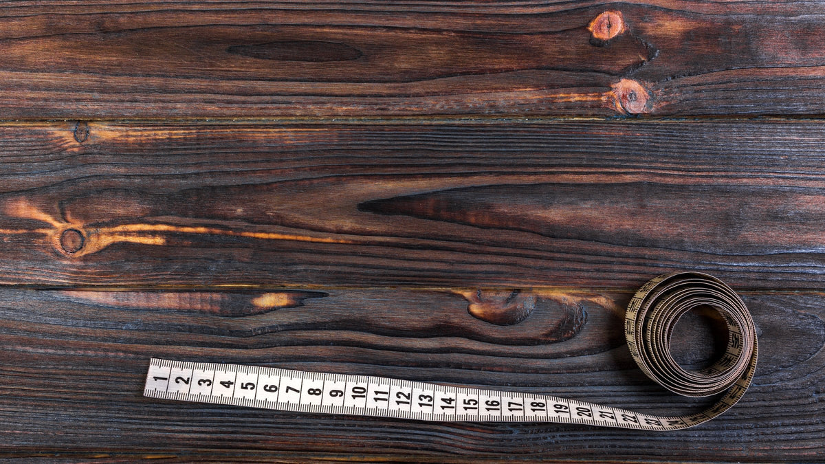 Measuring tape unrolled on dark brown wooden planks