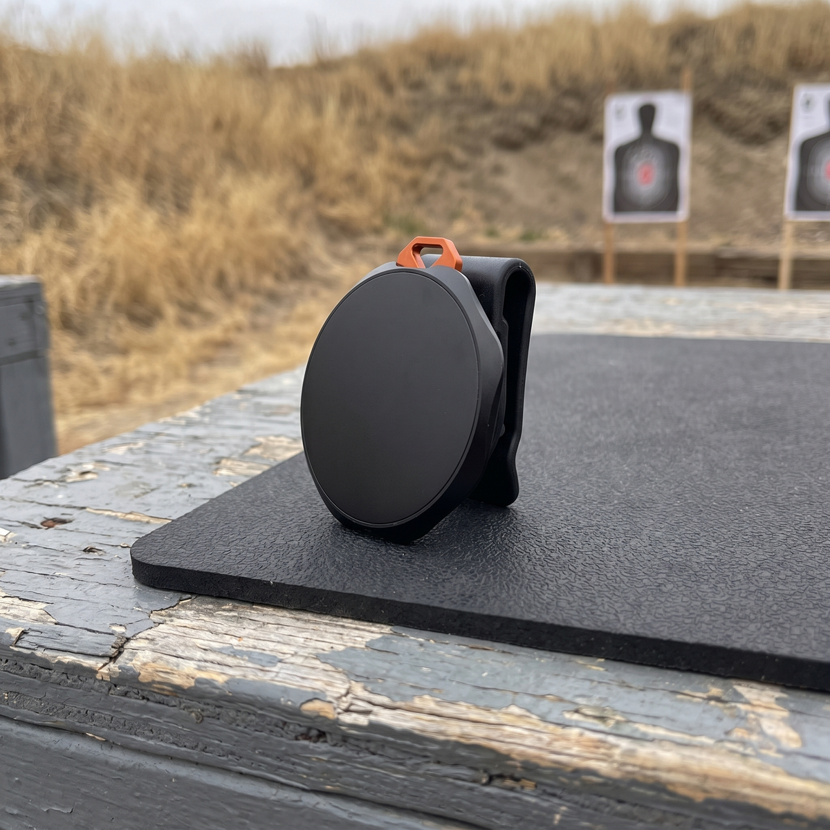 Magnetic Phone Mount: round magnetic face and clip, on an outdoor range bench, no phone